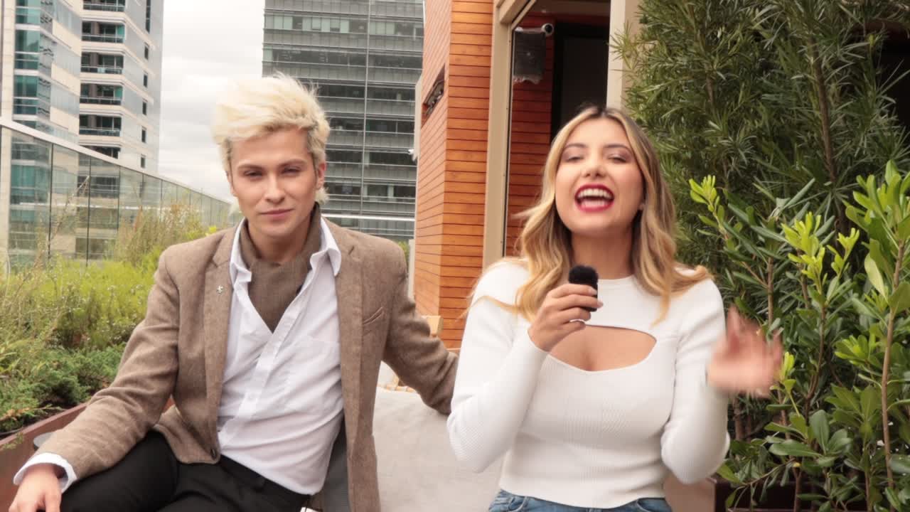 Entrevista grabada al aire libre: presentadora con micrófono junto a su invitado